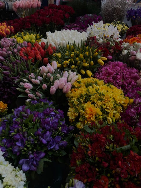 An array of fresh floral arrangements featuring a diverse selection of flowers in vibrant colors, including pink and purple tulips, yellow chrysanthemums, red roses, white lilies, and purple irises, a
