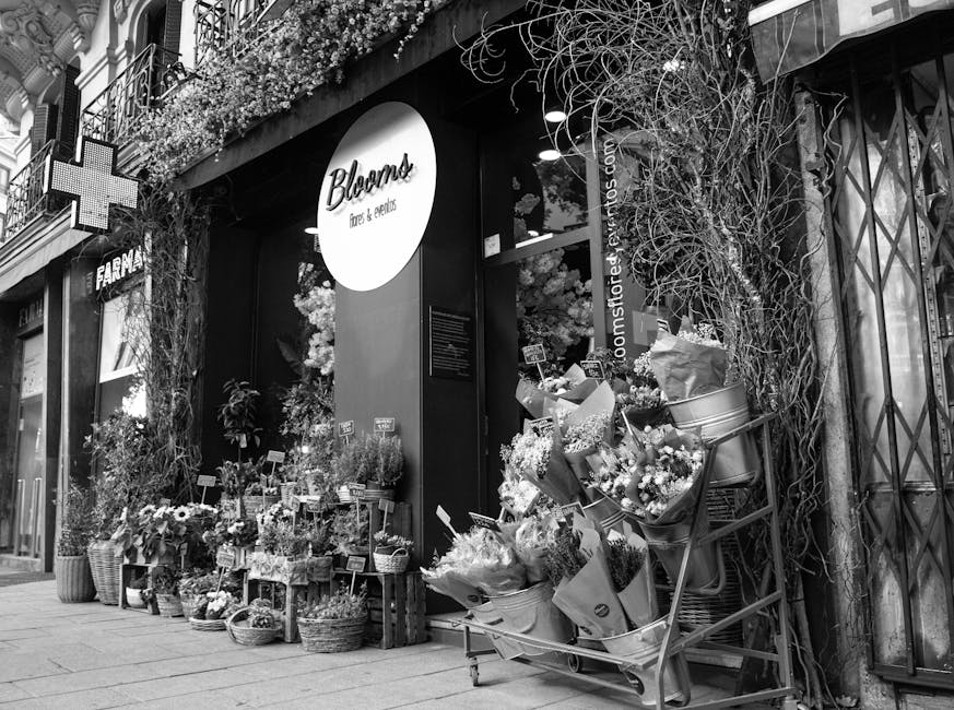 The storefront of Bloom's flowers & gifts, featuring an inviting display of freshly arranged floral bouquets and potted plants outside the shop. The flowers include a variety of seasonal blooms in dif