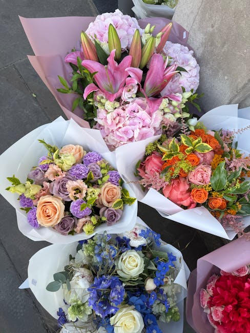 A collection of five vibrant floral bouquets arranged in white and pink wrapping paper, featuring a variety of fresh flowers including pink lilies, light pink hydrangeas, peach roses, purple lisianthu